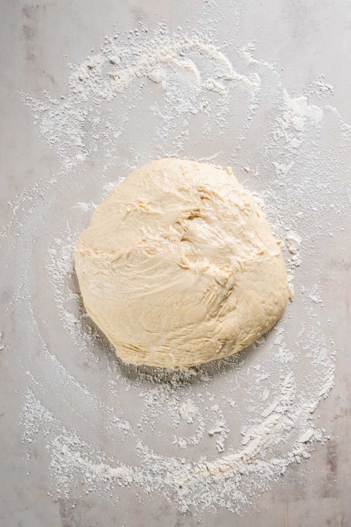 Ball of pizza dough on floured work surface.