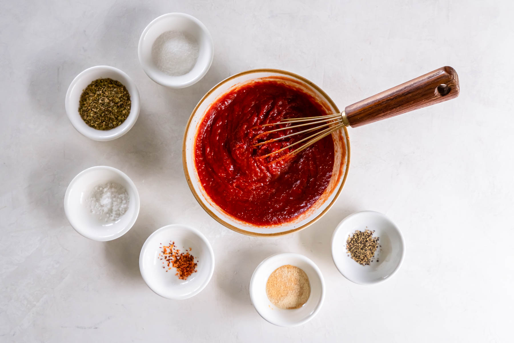 Tomato sauce and paste whisked together in bowl.