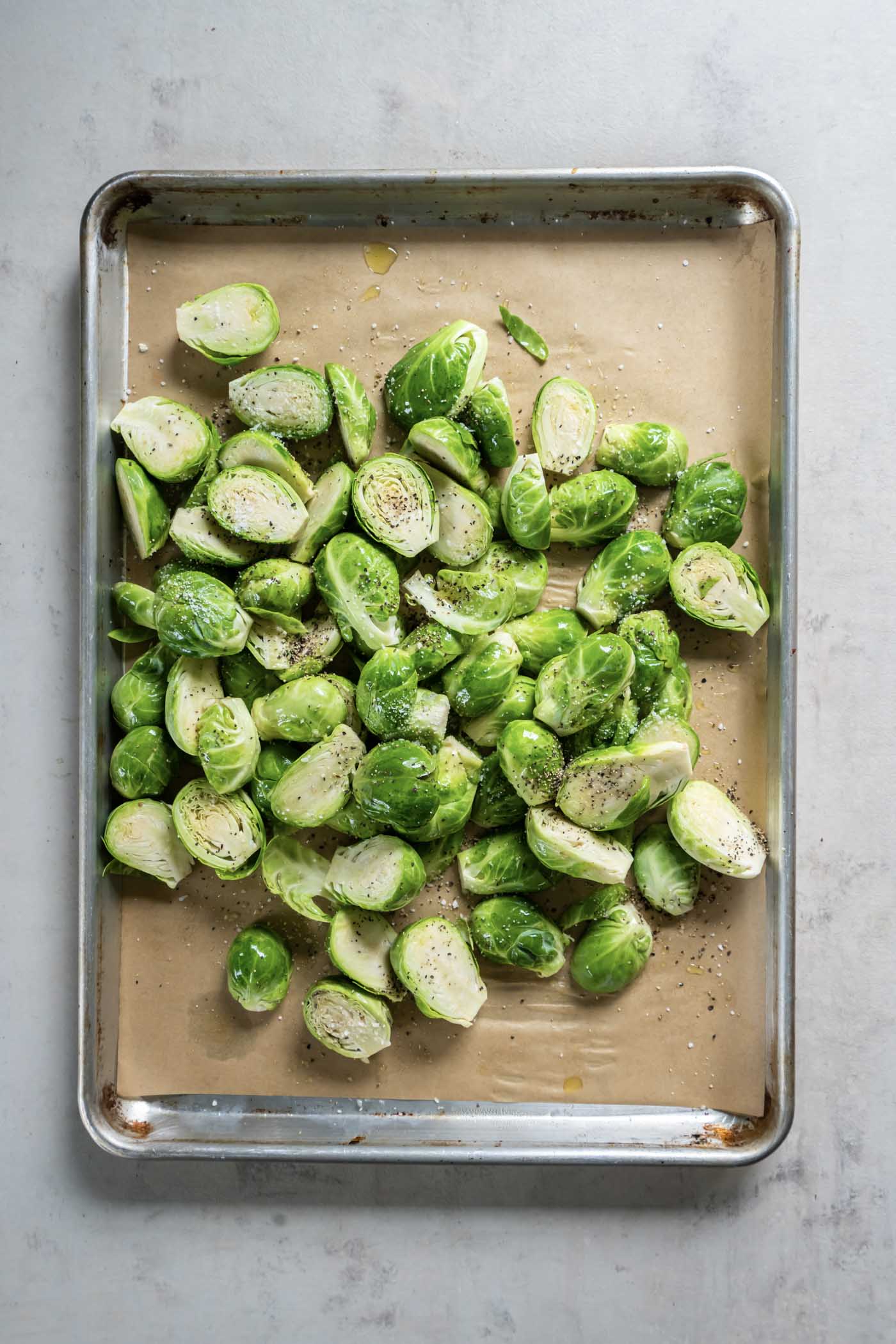 Halved brussels with olive oil, salt and pepper on parchment paper lined baking sheet.