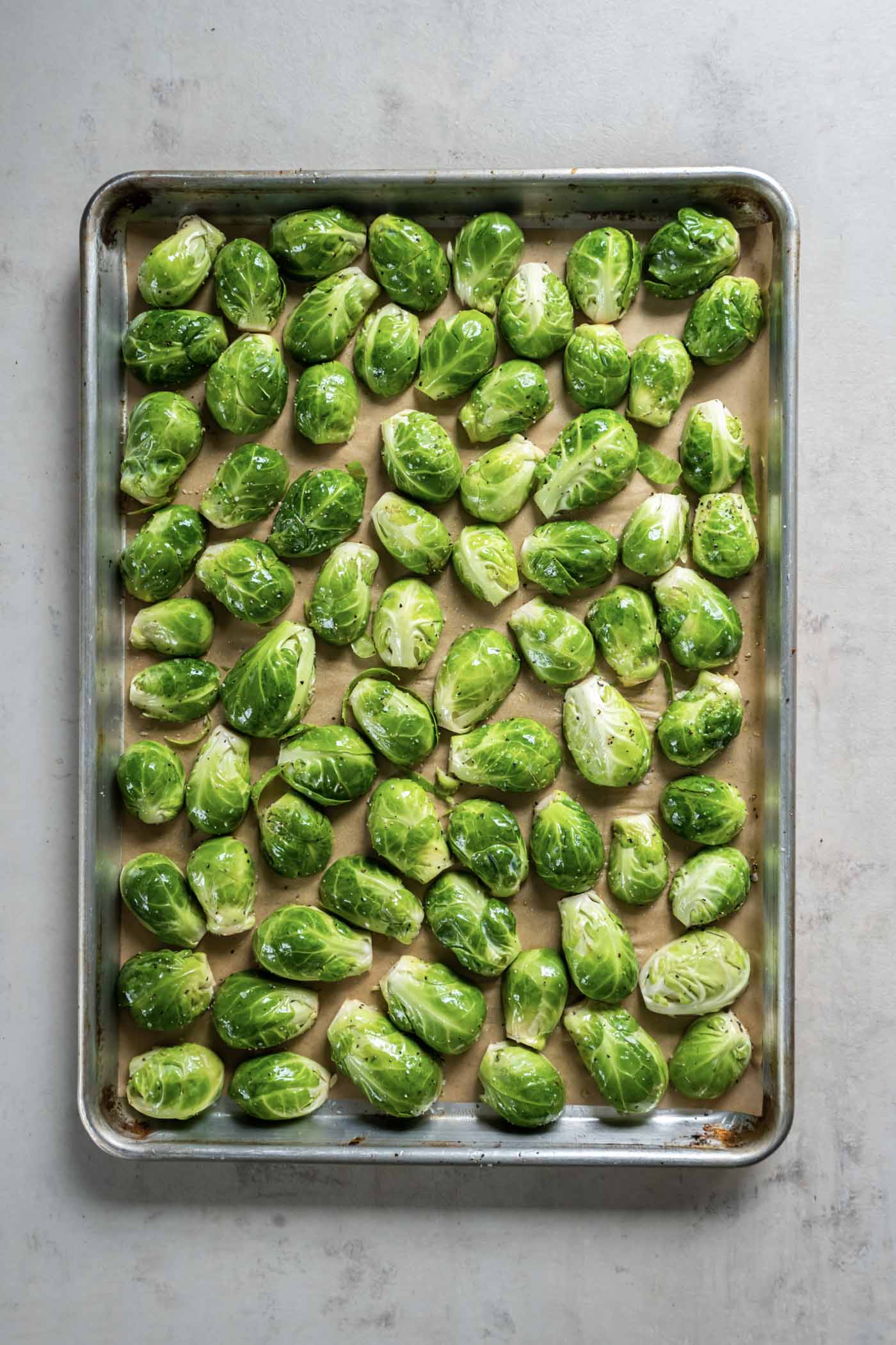 Uncooked brussels arranged cut side down on baking sheet.