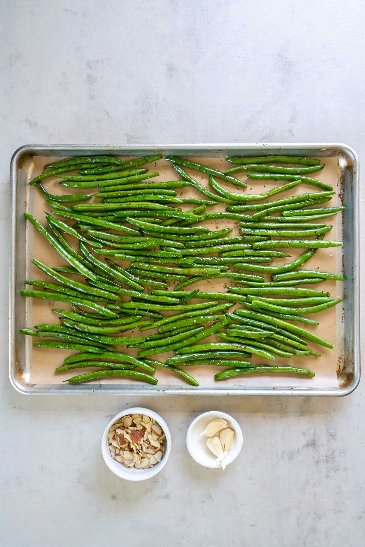 Seasoned green beans spread in an even layer on baking sheet.