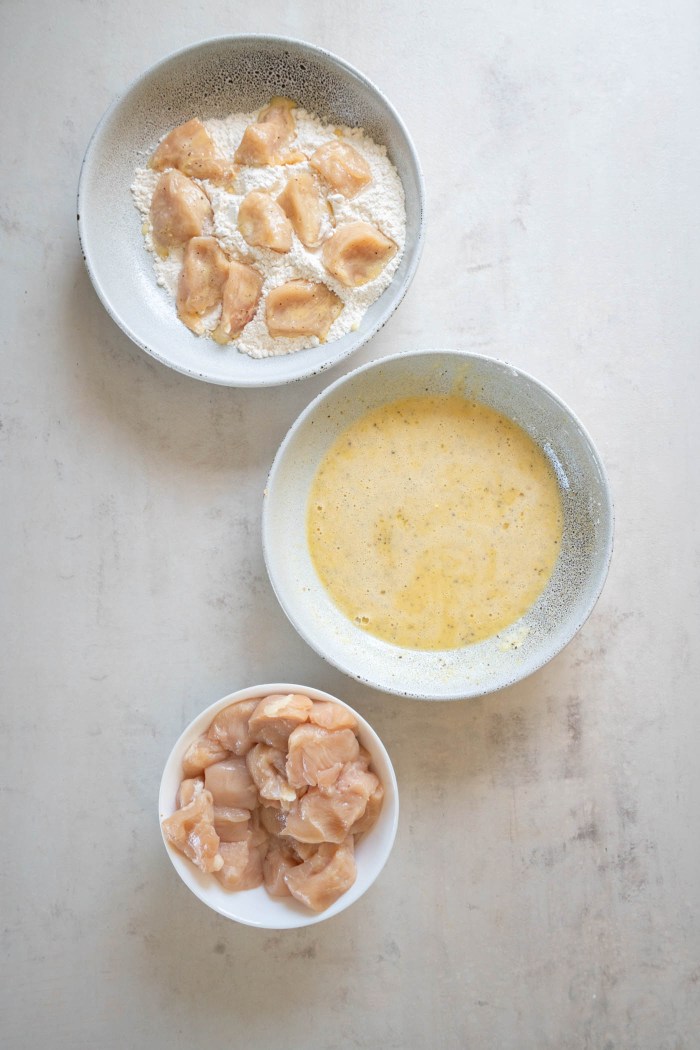 Coating chicken pieces in flour.