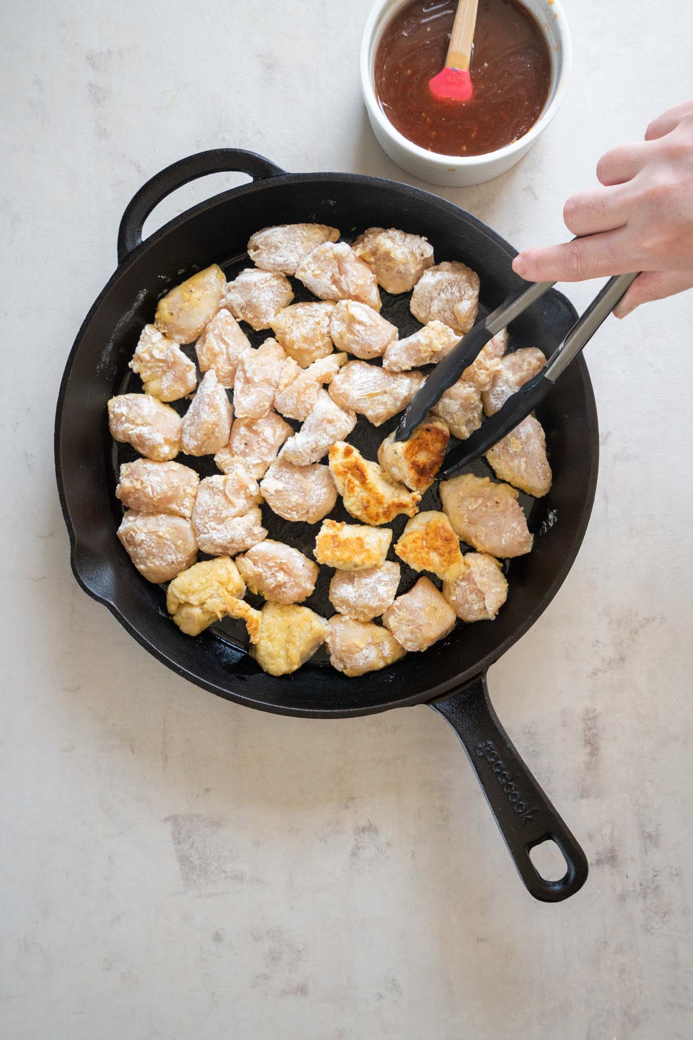 Browning chicken pieces in a cast iron skillet.