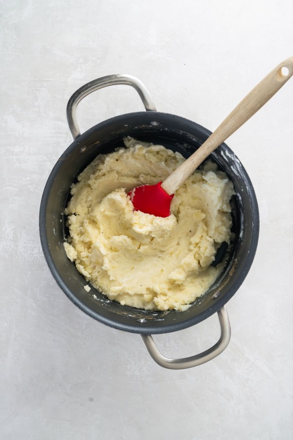 Mashed potatoes in pot with spatula.