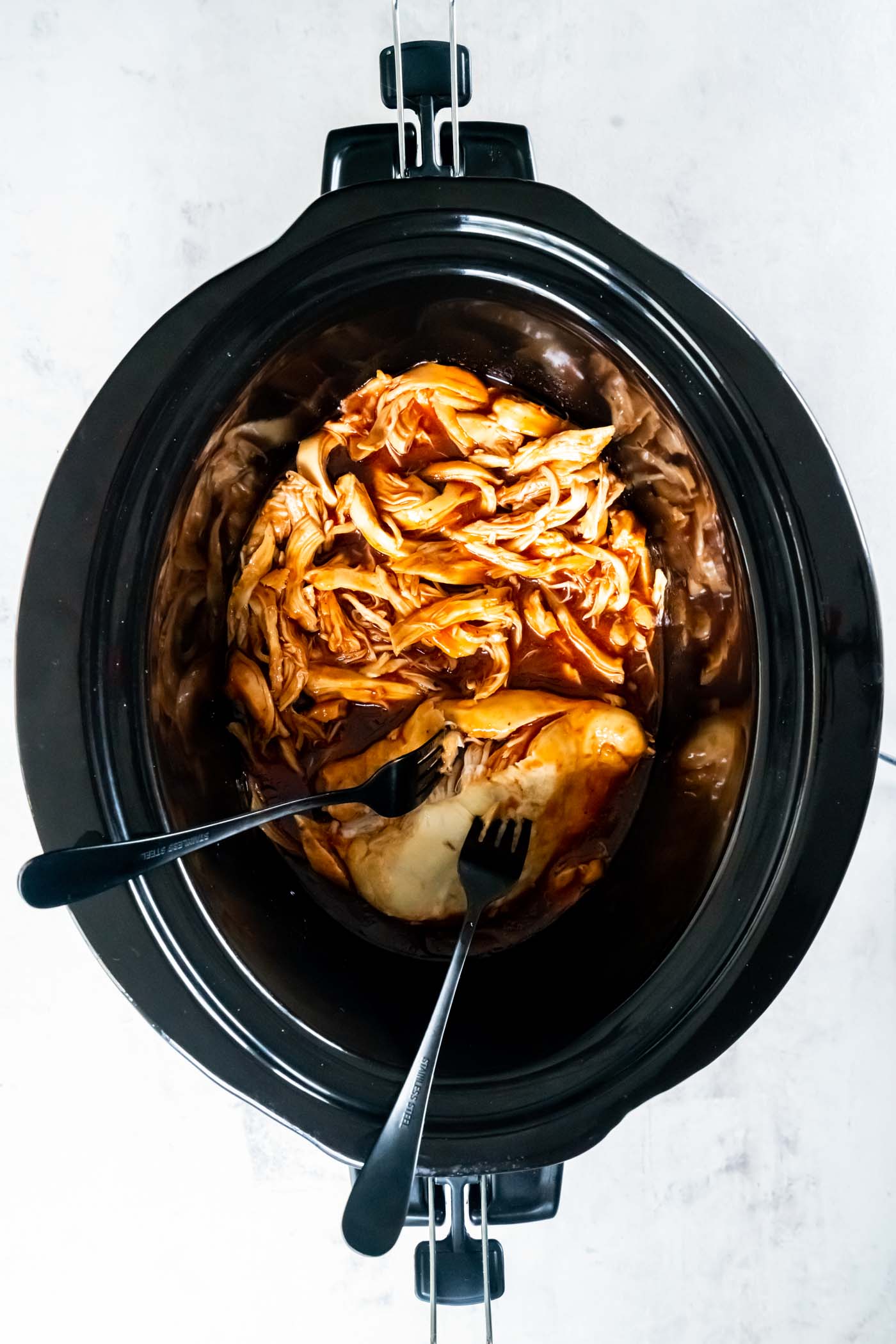 Using two forks to shred bbq chicken in slow cooker.