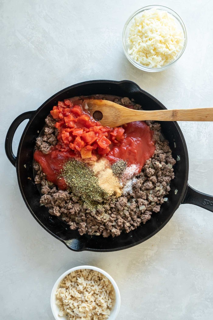 Tomato sauce, diced tomatoes and seasonings added to browned beef and onion in skillet.