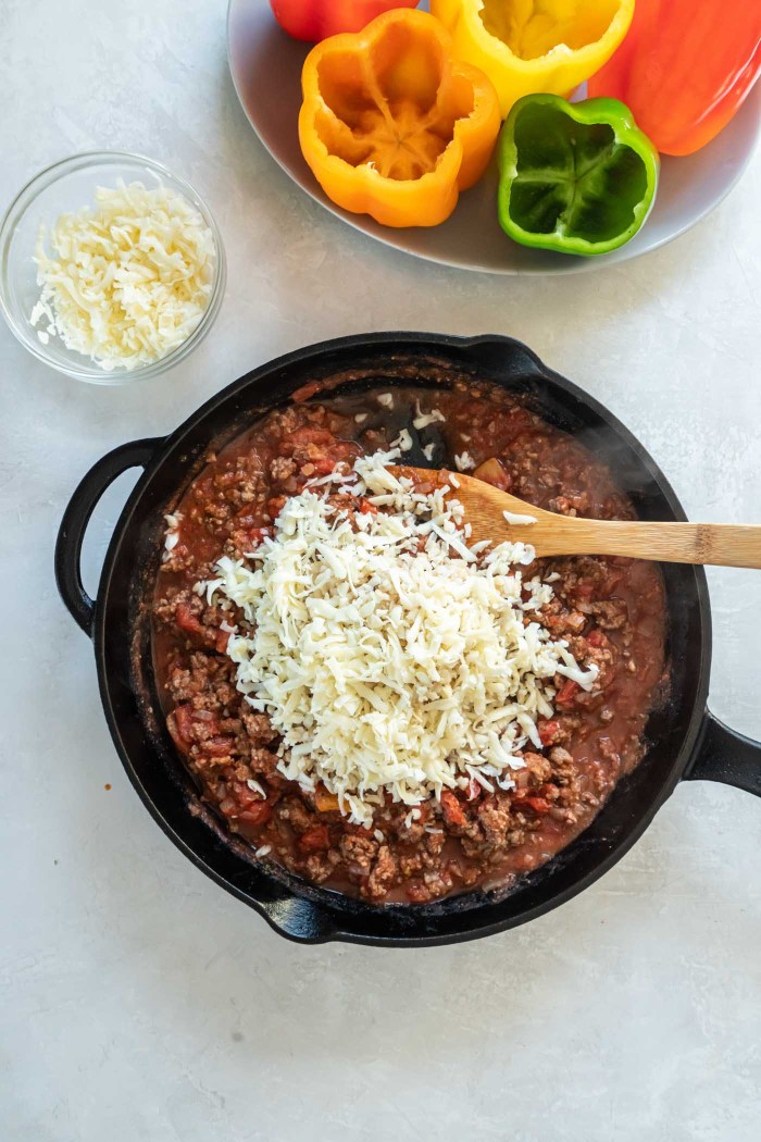Rice and shredded mozzarella added to browned ground beef and tomato sauce in skillet.