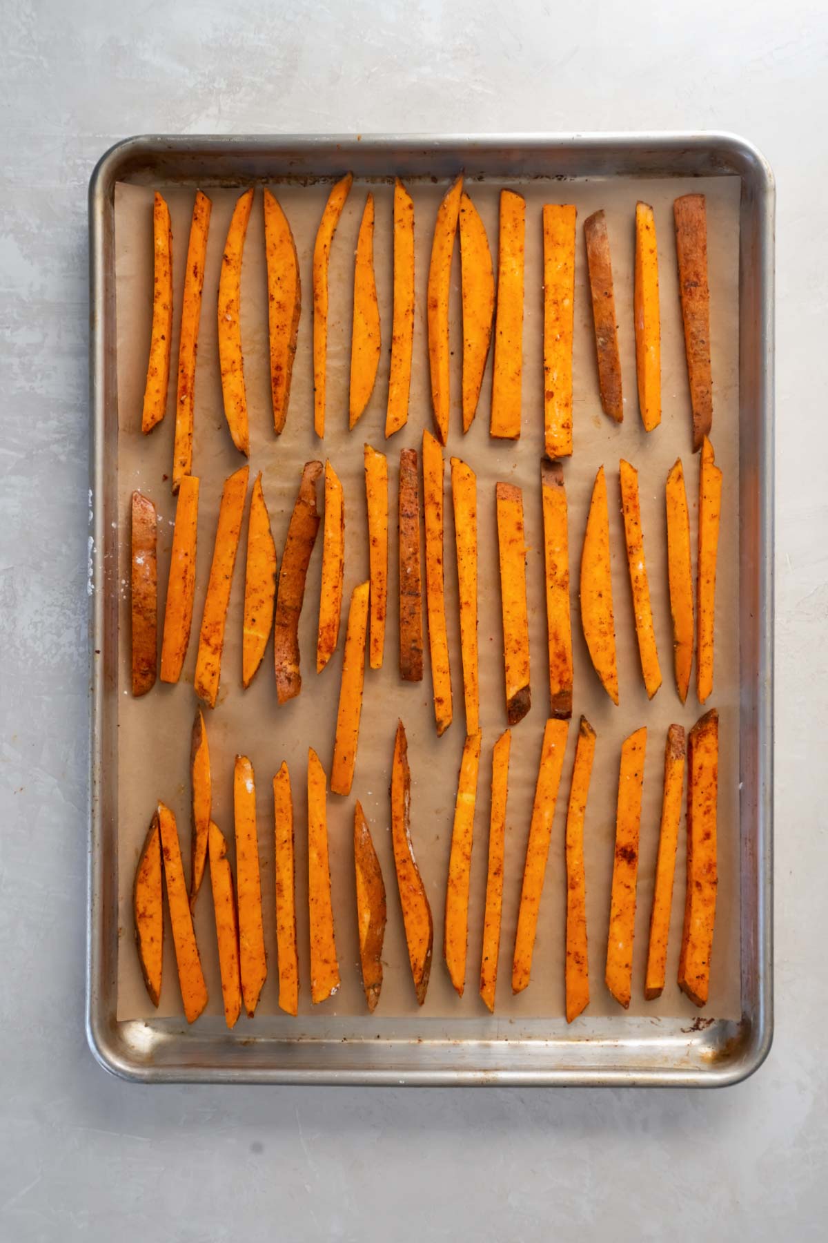 Unbaked sweet potato fries in a single layer on baking sheet.