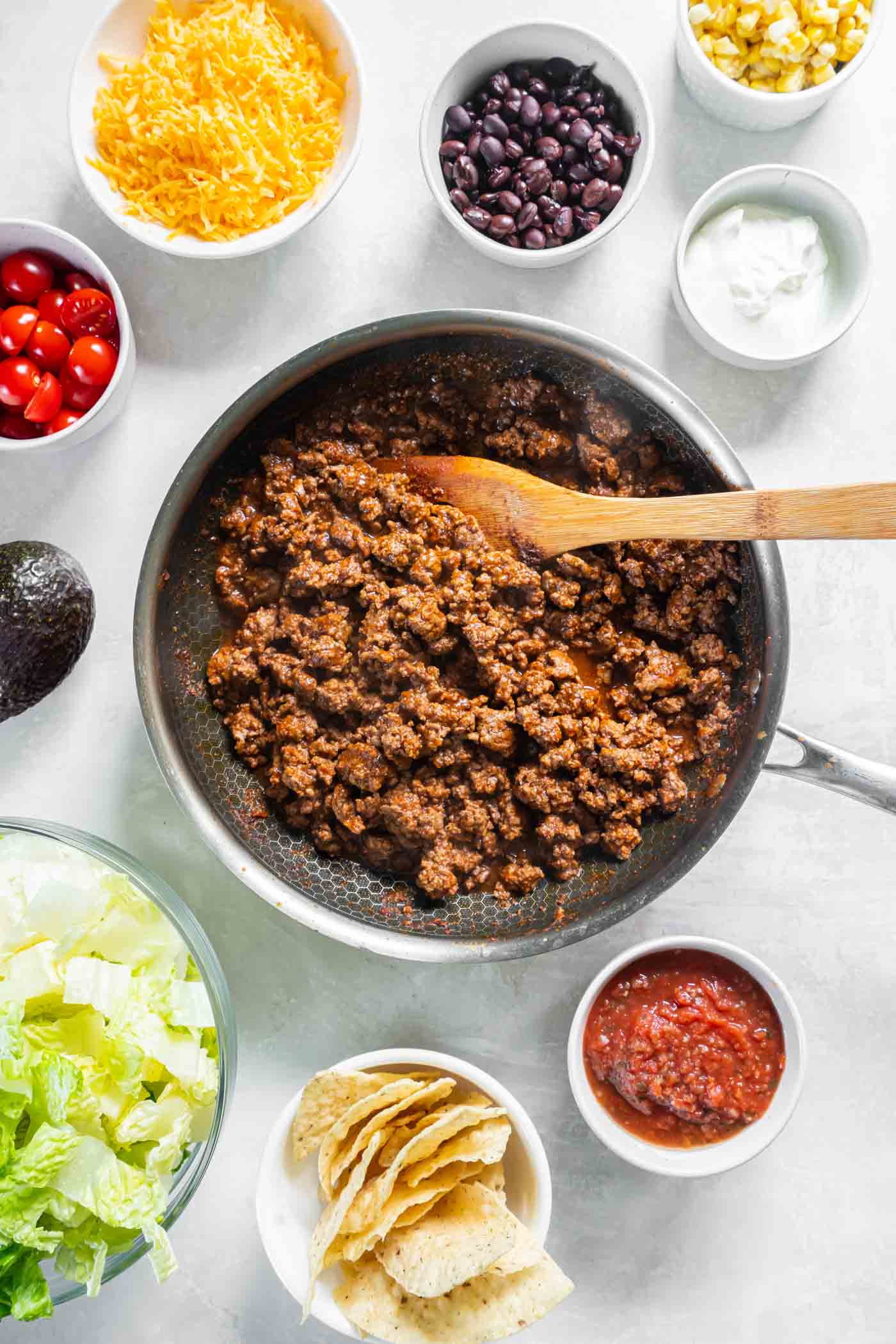Cooked taco meat in a skillet with a wooden spoon.