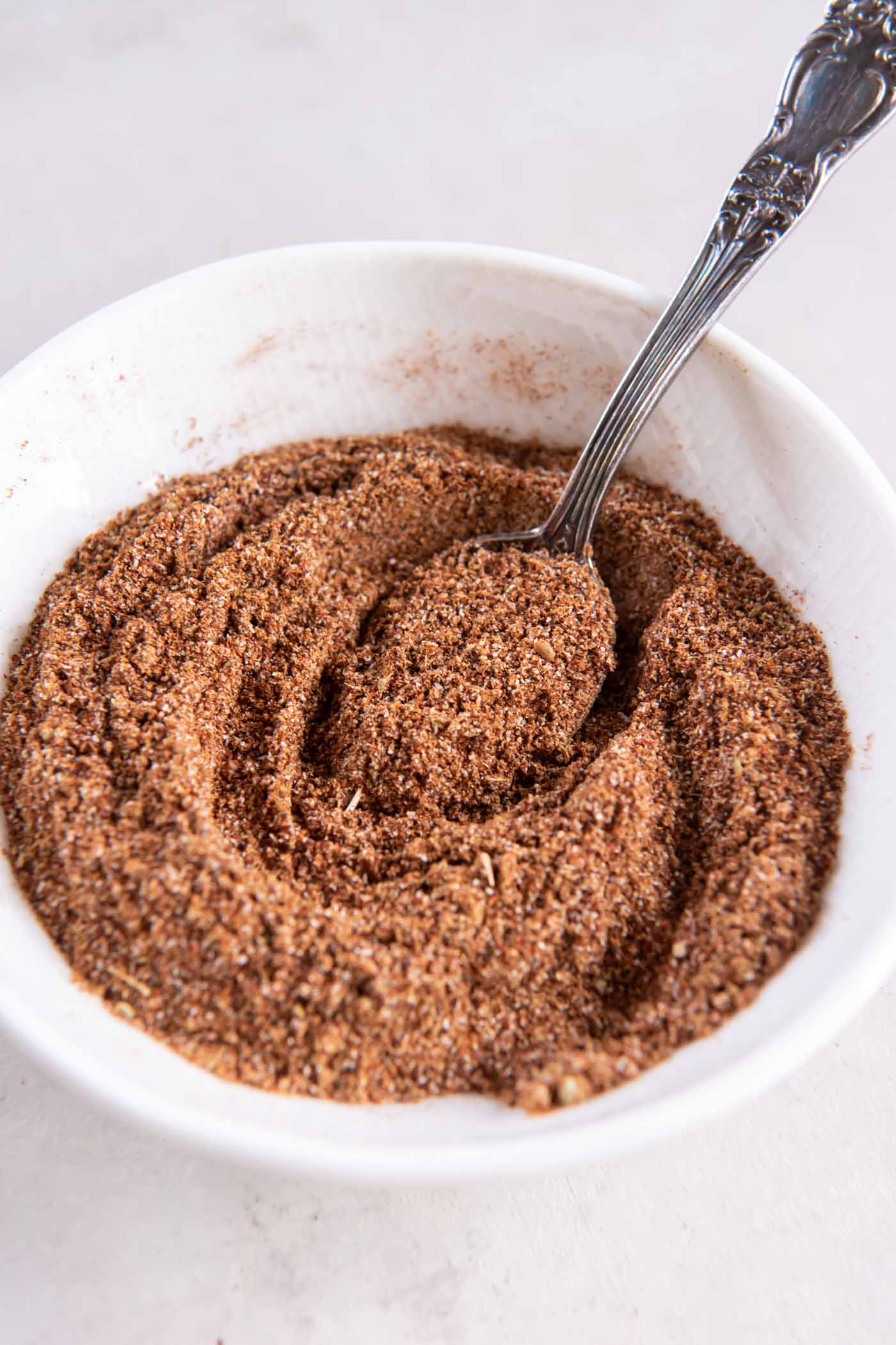 Homemade taco seasoning in a small bowl with a spoon.