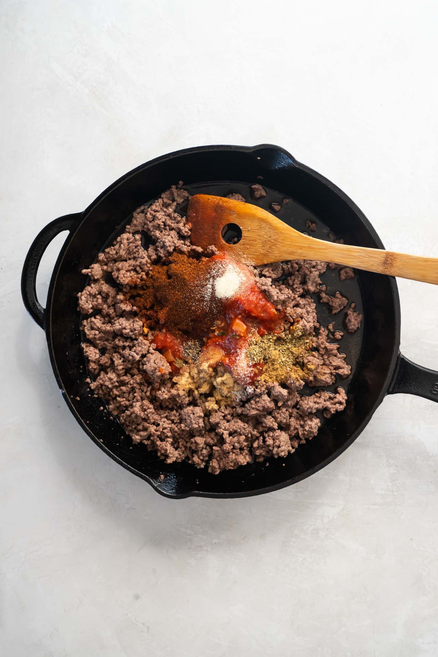 Tomato sauce, water and seasonings added to browned ground beef in skillet.
