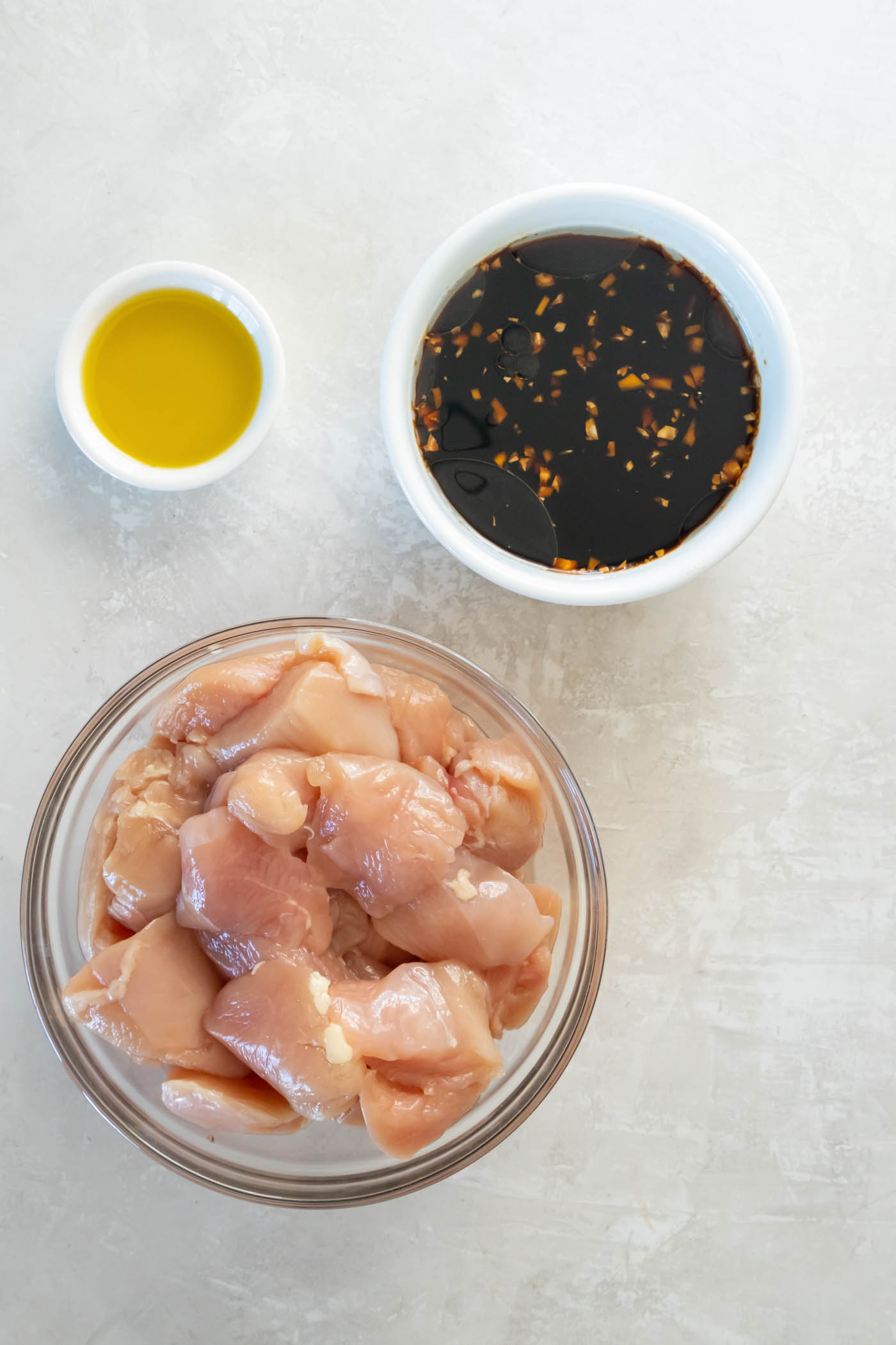 Teriyaki sauce ingredients combined in a bowl with dish of oil and bowl of chopped chicken next to it.