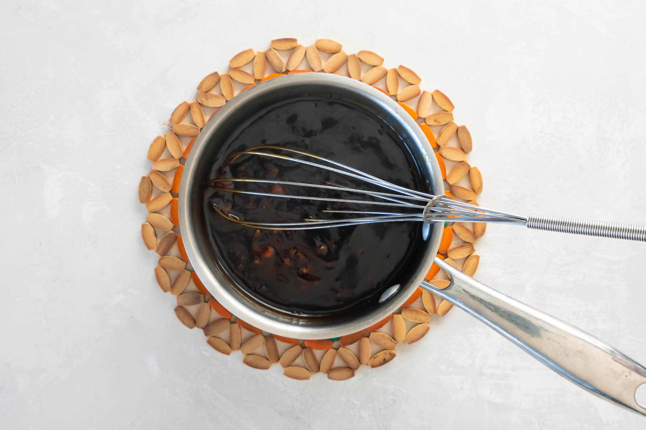 Teriyaki sauce in a small saucepan with a whisk.