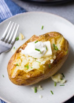 Instant Pot baked potato topped with salt, pepper, butter, sour cream and chives.