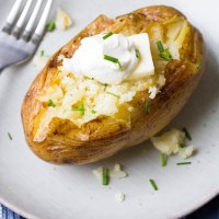 Instant pot baked potato topped with butter, salt, pepper, sour cream and chives.