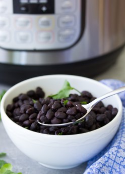 Instant Pot black beans in a white serving bowl, with an Instant Pot in the background.