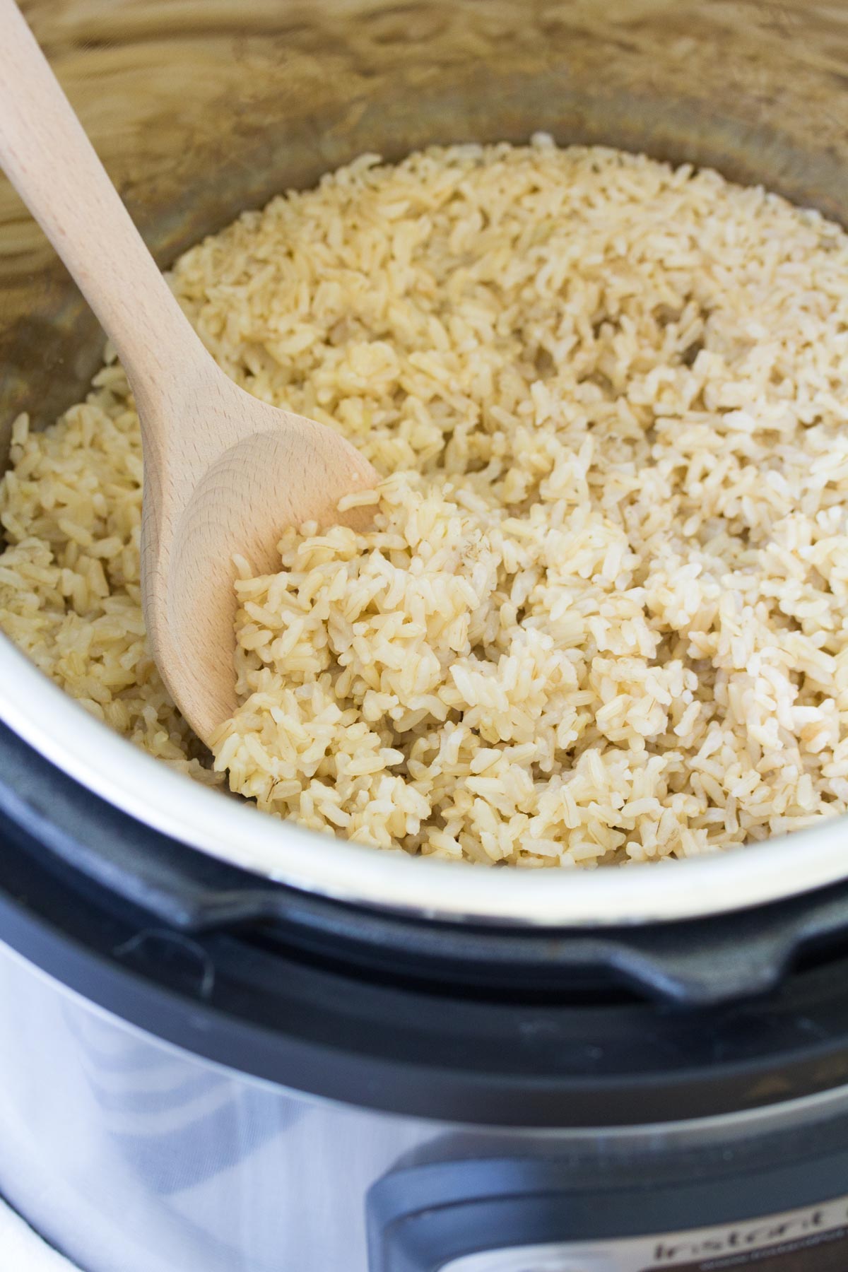 Cooked brown rice in an instant pot with a wooden spoon.
