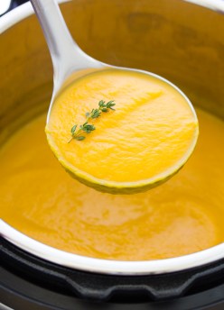 Butternut squash soup in a ladle spoon over an Instant Pot full of soup.