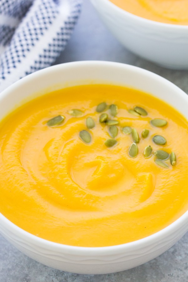 Butternut squash soup served in a white bowl and garnished with pumpkin seeds.