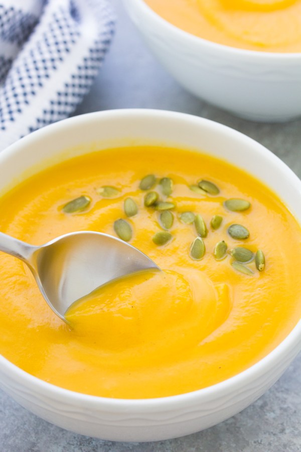 A bowl full of creamy instant pot butternut squash soup, with a spoon scooping up a bite.