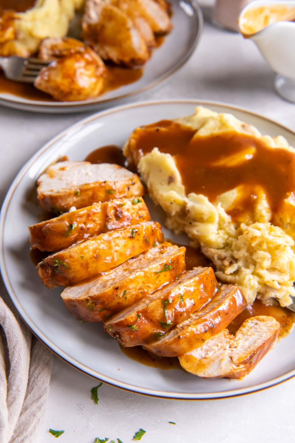 Sliced instant pot chicken breast served with gravy and mashed potatoes.