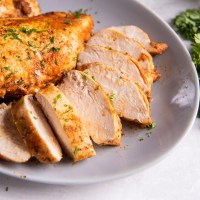 Close up of Instant Pot chicken breasts on a plate with one breast sliced.
