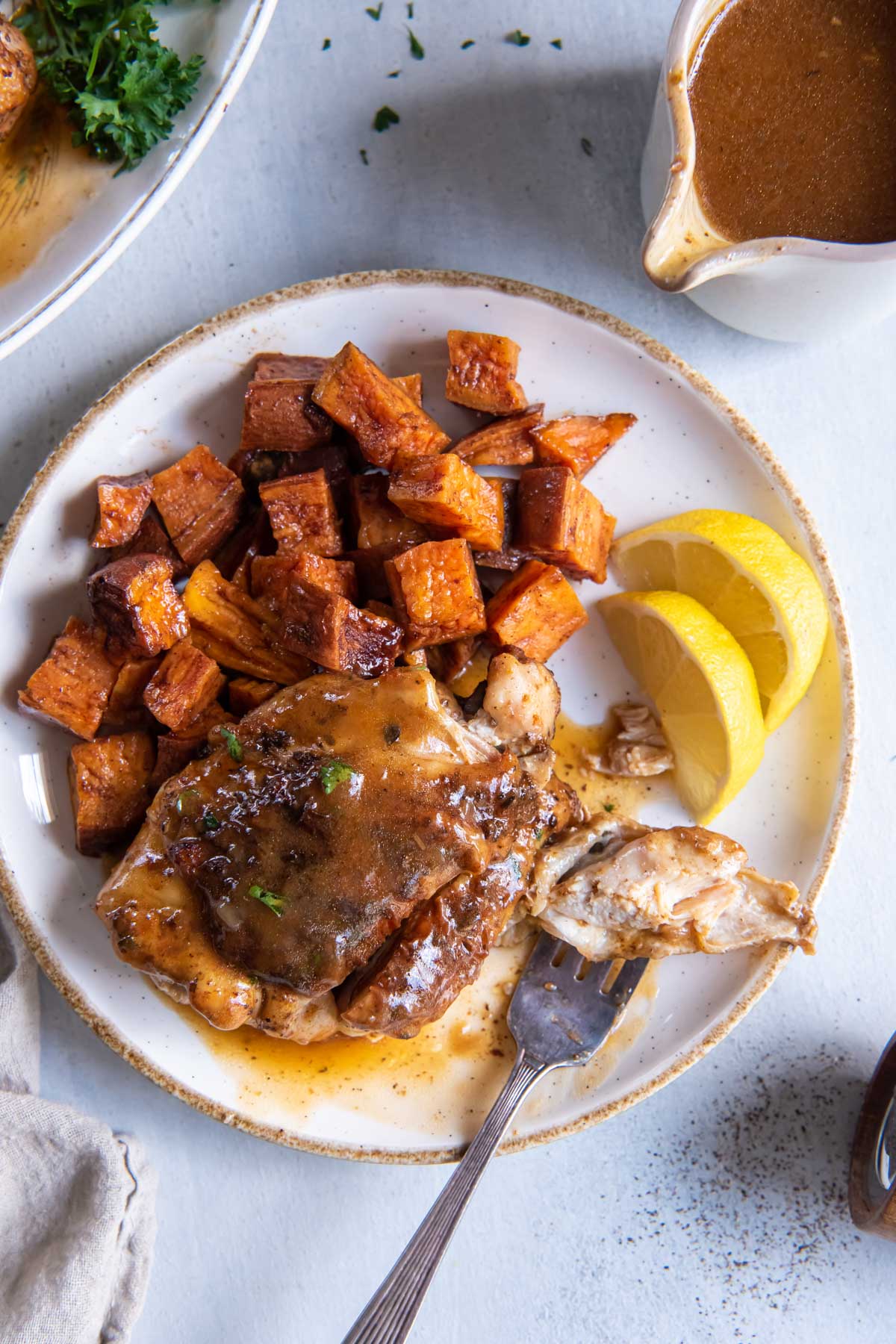 Instant Pot chicken thigh served with gravy and roasted sweet potatoes.