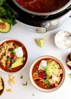 Two bowls of instant pot chicken tortilla soup with toppings with instant pot in background.