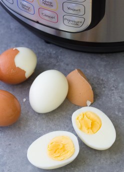 Instant Pot hard boiled eggs with the shells falling off and one cooked egg cut in half.