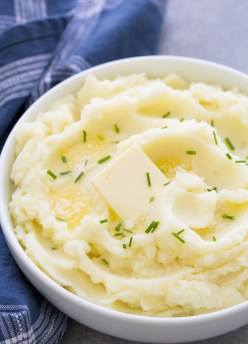 instant pot mashed potatoes in a serving bowl with butter and chives