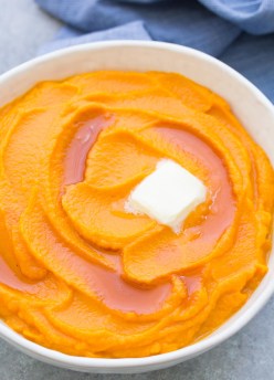 Mashed sweet potatoes in a white serving bowl.