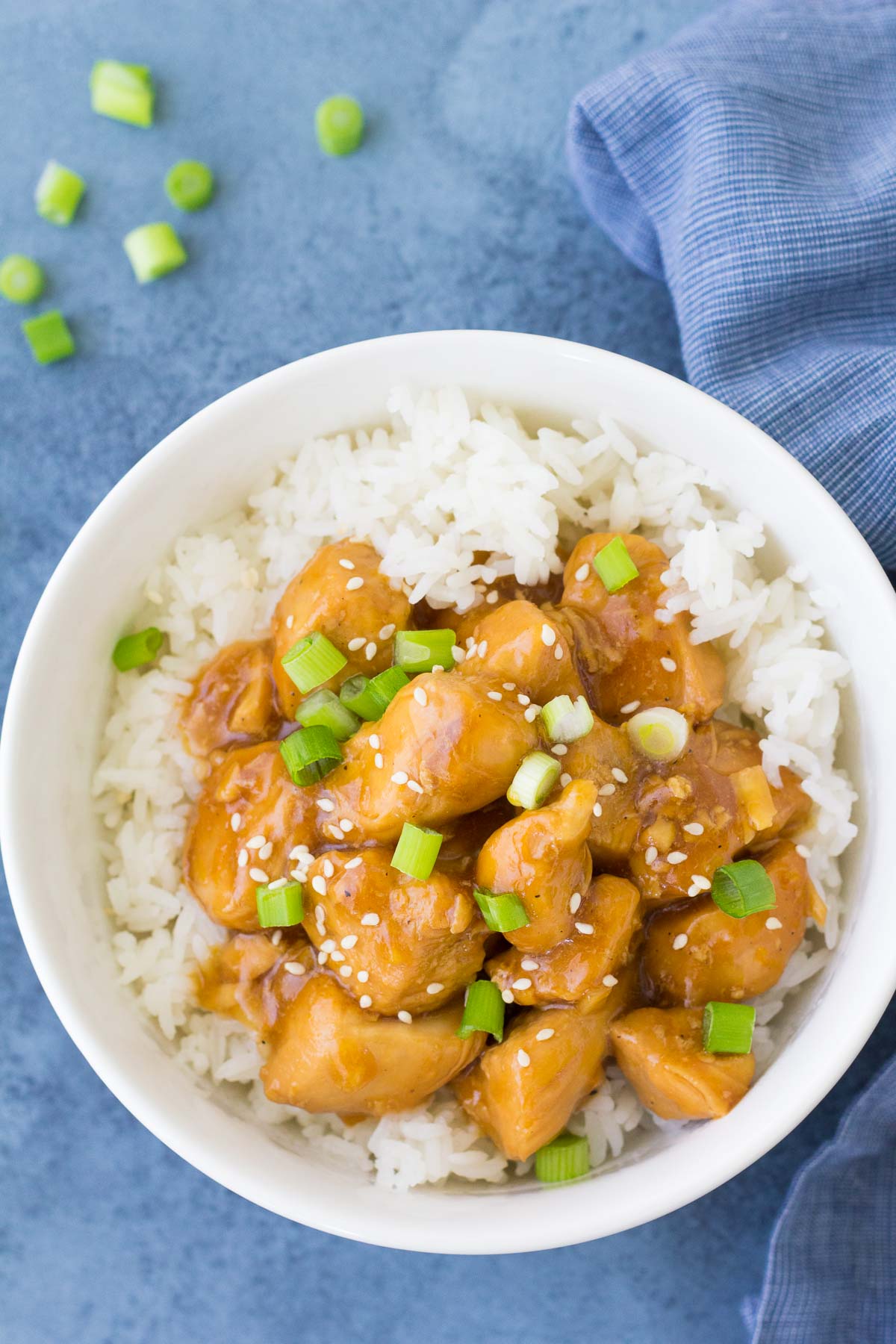Instant pot orange chicken served over white rice, topped with green onions.