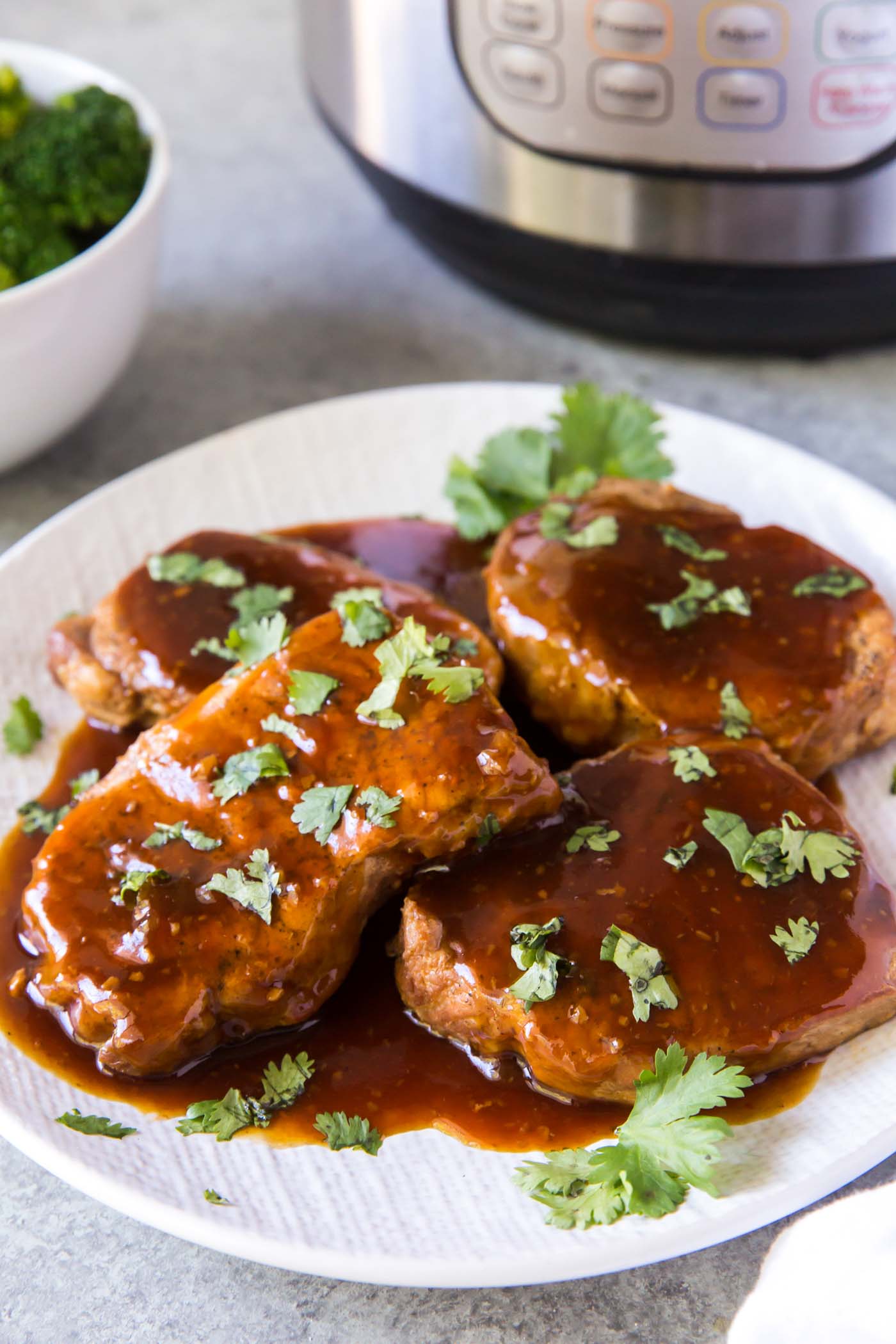 Four instant pot pork chops with honey garlic sauce on a serving plate.