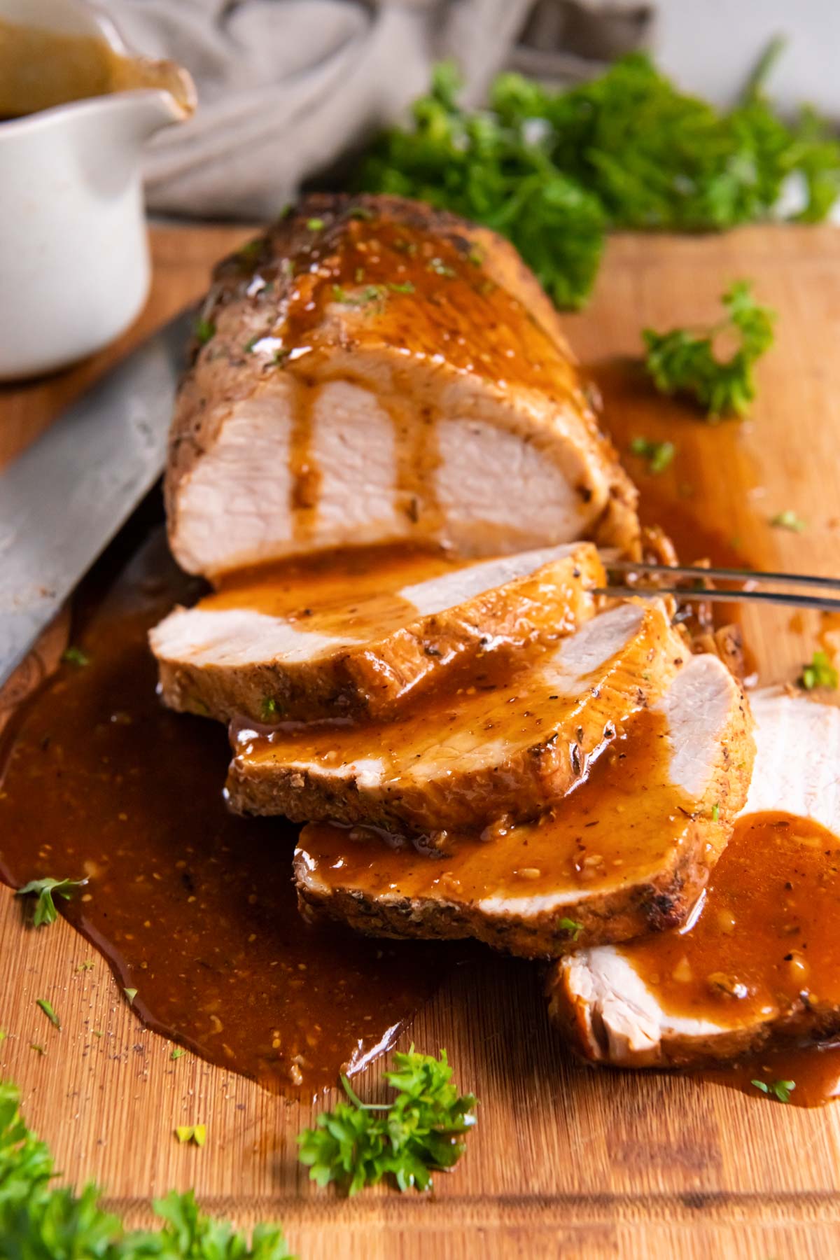Partially sliced Instant Pot pork loin with gravy drizzled over it.