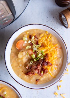Bowl of instant pot potato soup topped with bacon, cheese and green onions.