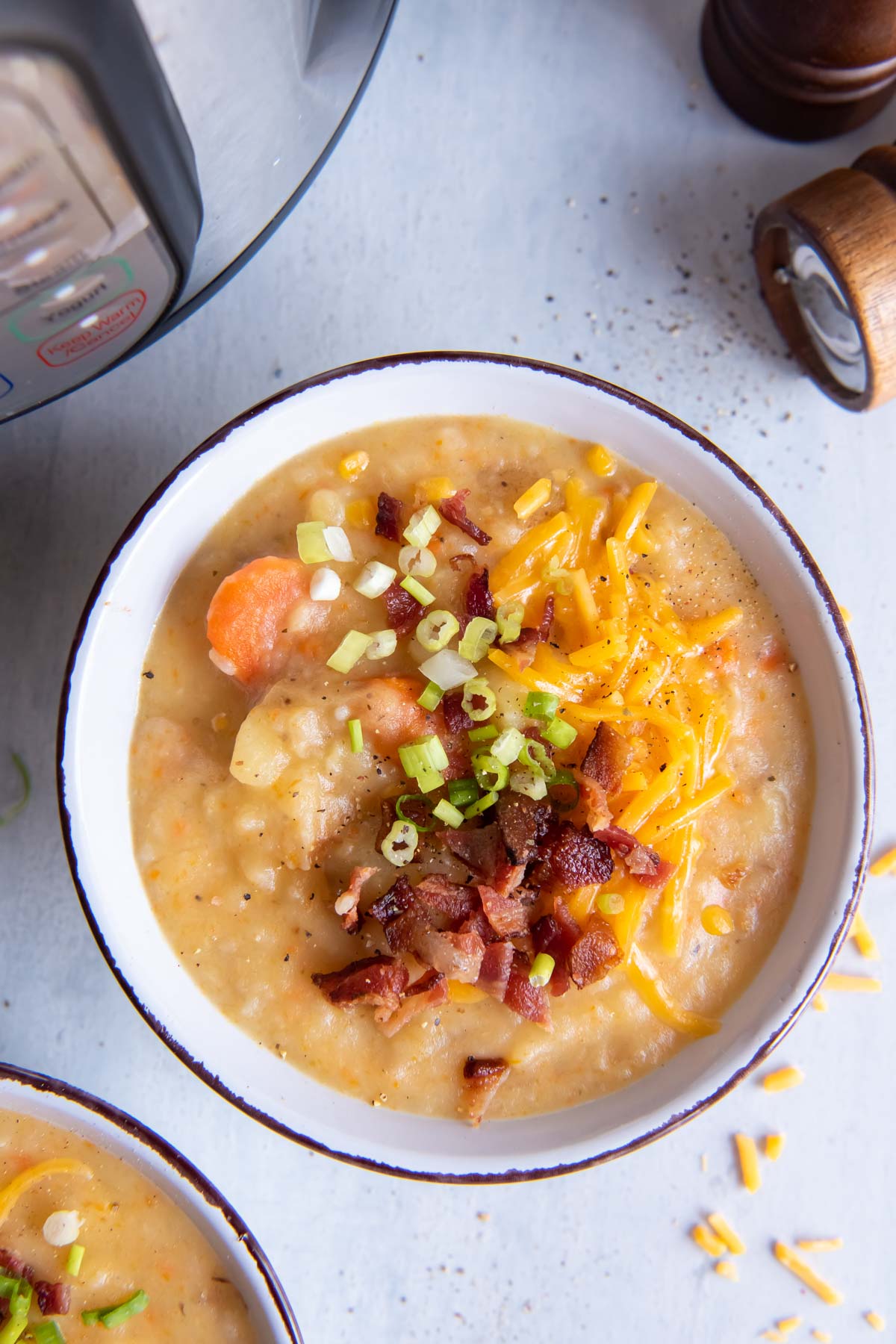 Bowl of instant pot potato soup topped with bacon, cheese and green onions.