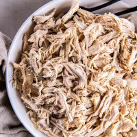 Shredded chicken in a bowl with two forks.