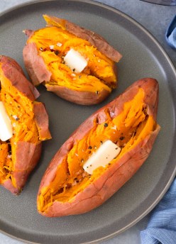 Baked Instant Pot sweet potatoes with butter, salt and pepper on a gray plate.
