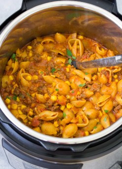 Cheesy taco pasta in an Instant Pot with a serving spoon.