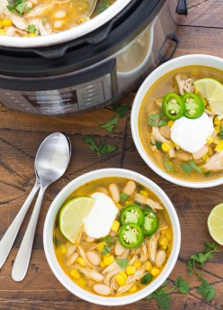 Two bowls of white chicken chili with toppings, next to an Instant Pot full of chili.