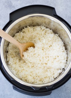 Cooked white rice in an Instant Pot pressure cooker, with a wooden spoon.