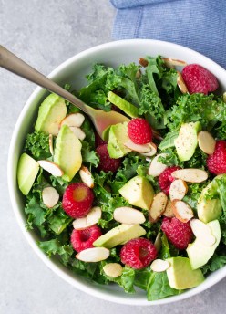Kale avocado salad in a white bowl with a fork.