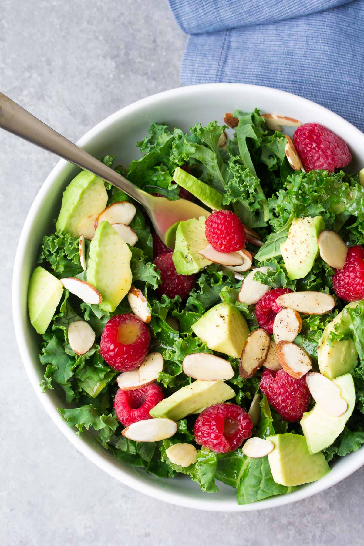 Kale avocado salad in a white bowl with a fork.