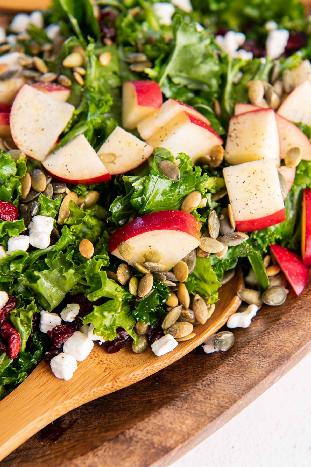 close up of kale salad with apples, cranberries, pepitas and goat cheese