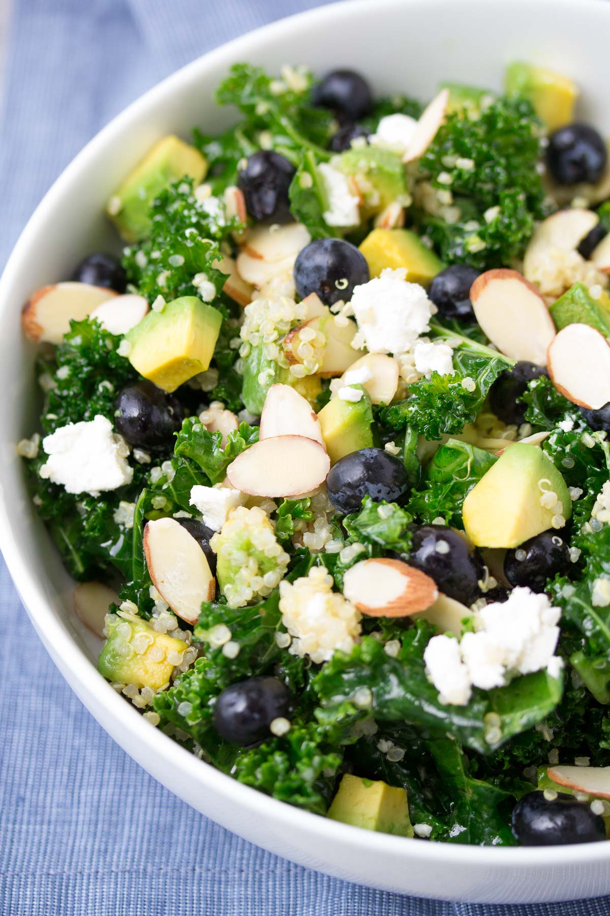 Kale Avocado Salad with quinoa and blueberries in a white bowl.