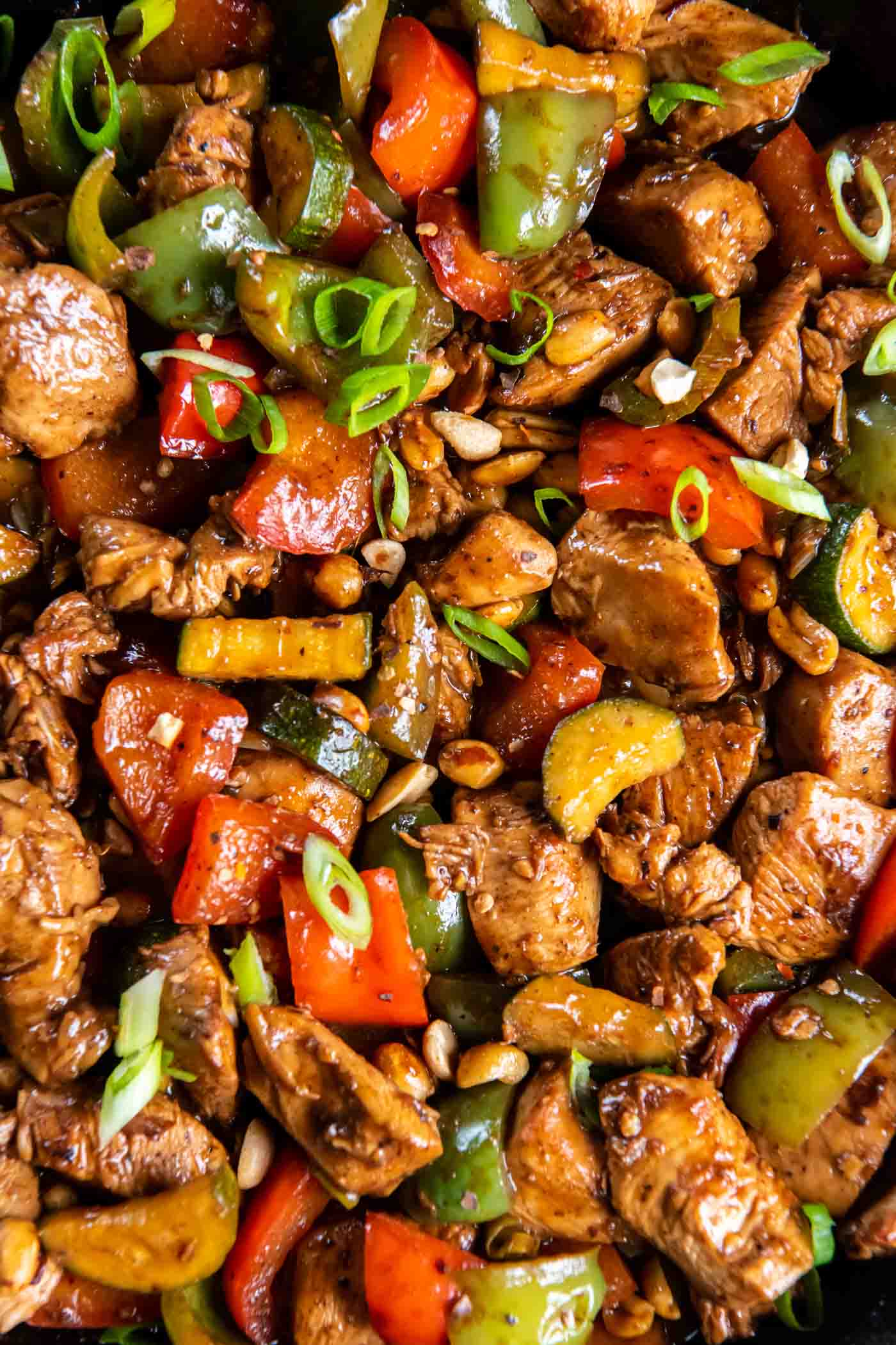 Close up of kung pao chicken with sliced green onion garnish.
