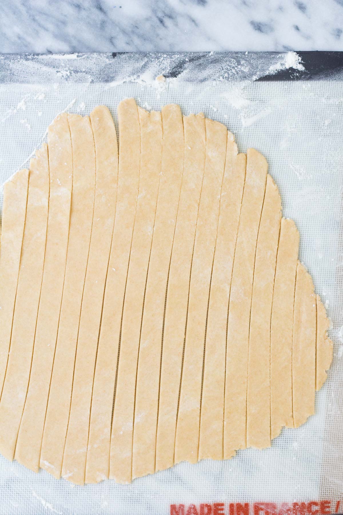 Rolled out pie dough round cut into strips.