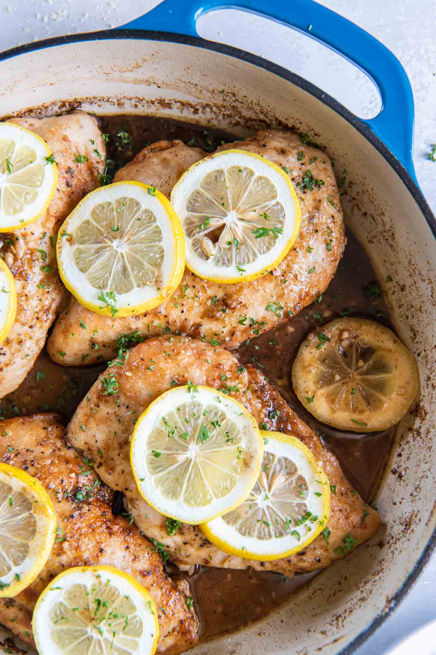 Lemon chicken breasts with fresh lemon slices in a braiser pot.