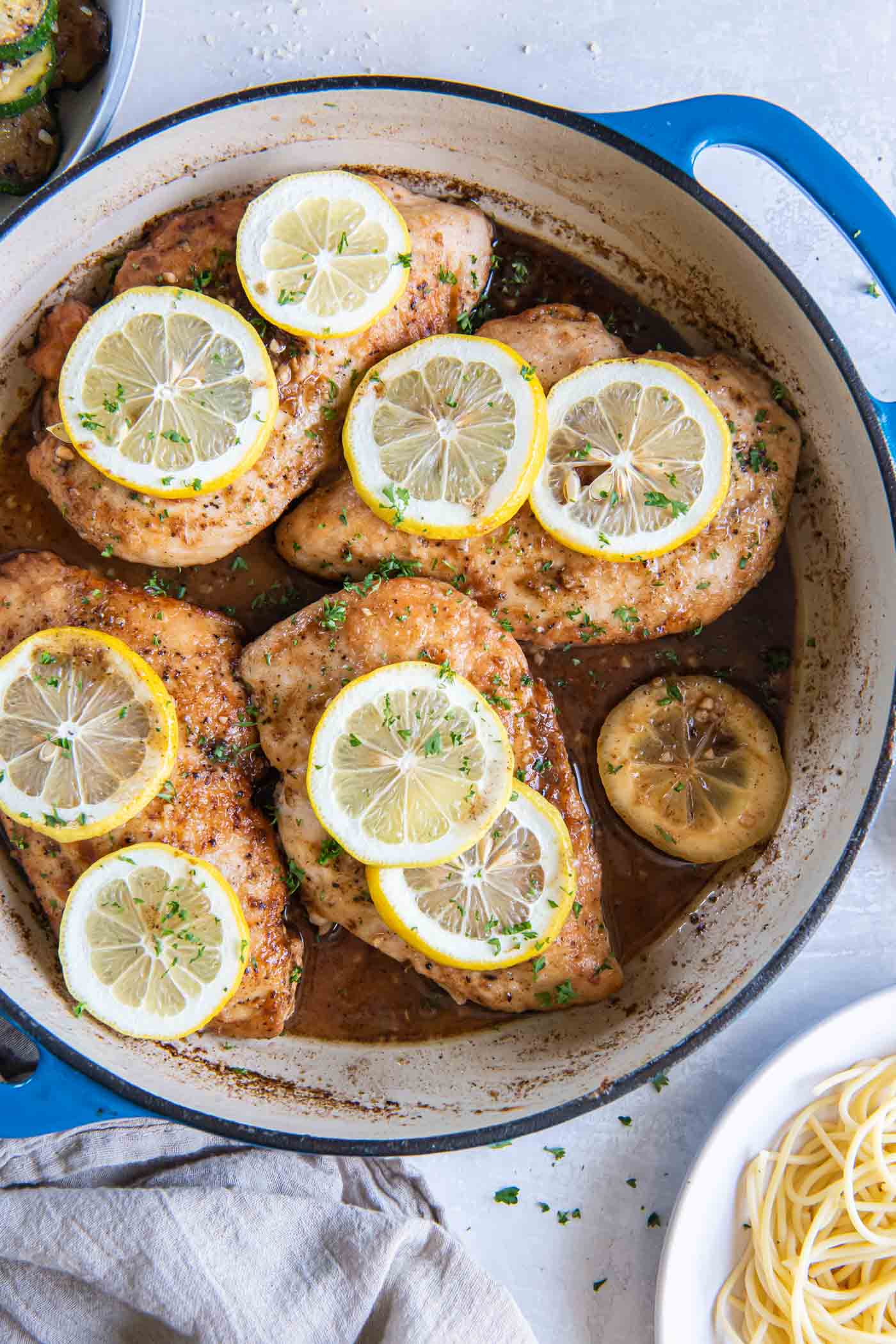 Lemon chicken breasts with fresh lemon slices in a braiser pot.