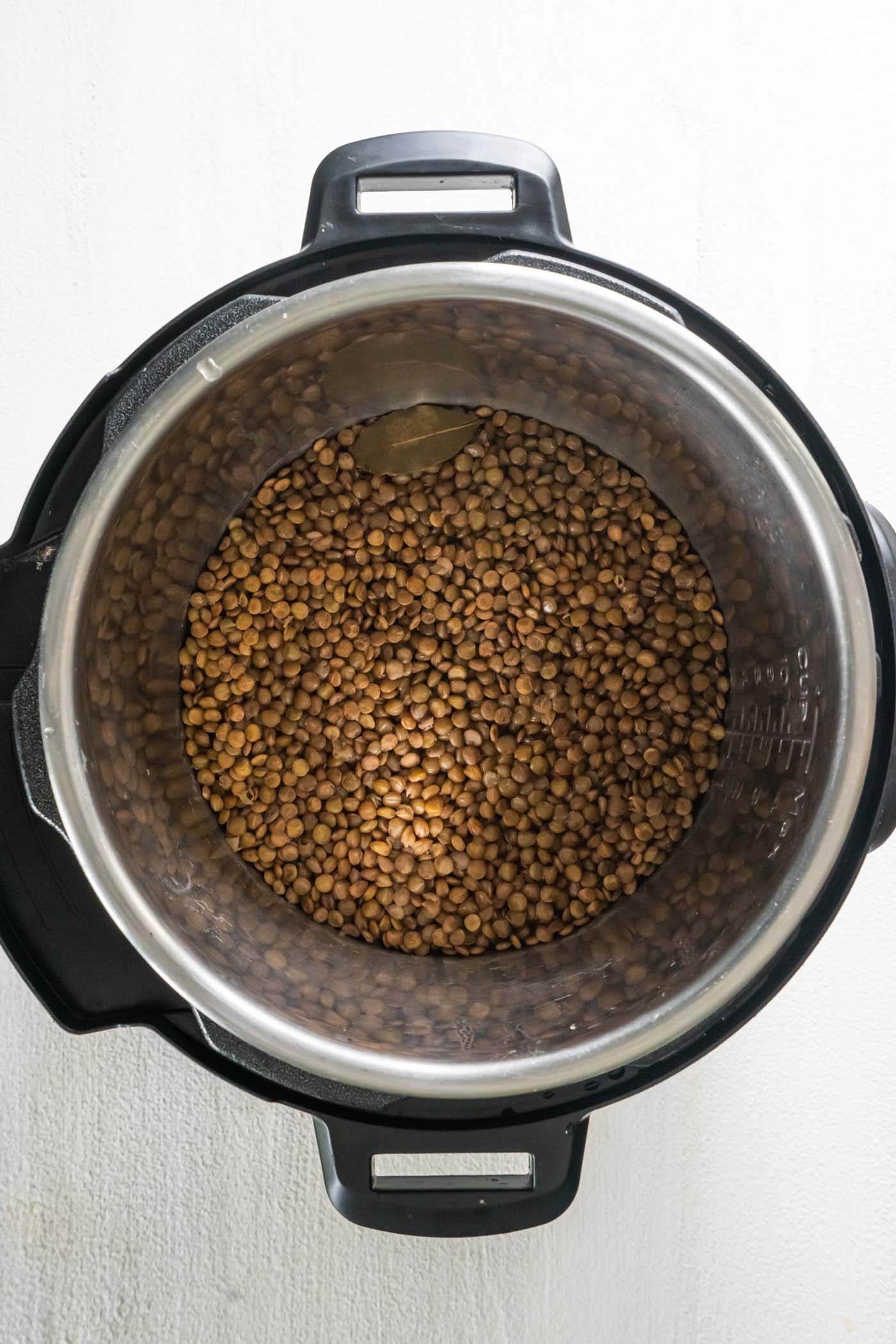 Cooked lentils in instant pot with bay leaf.